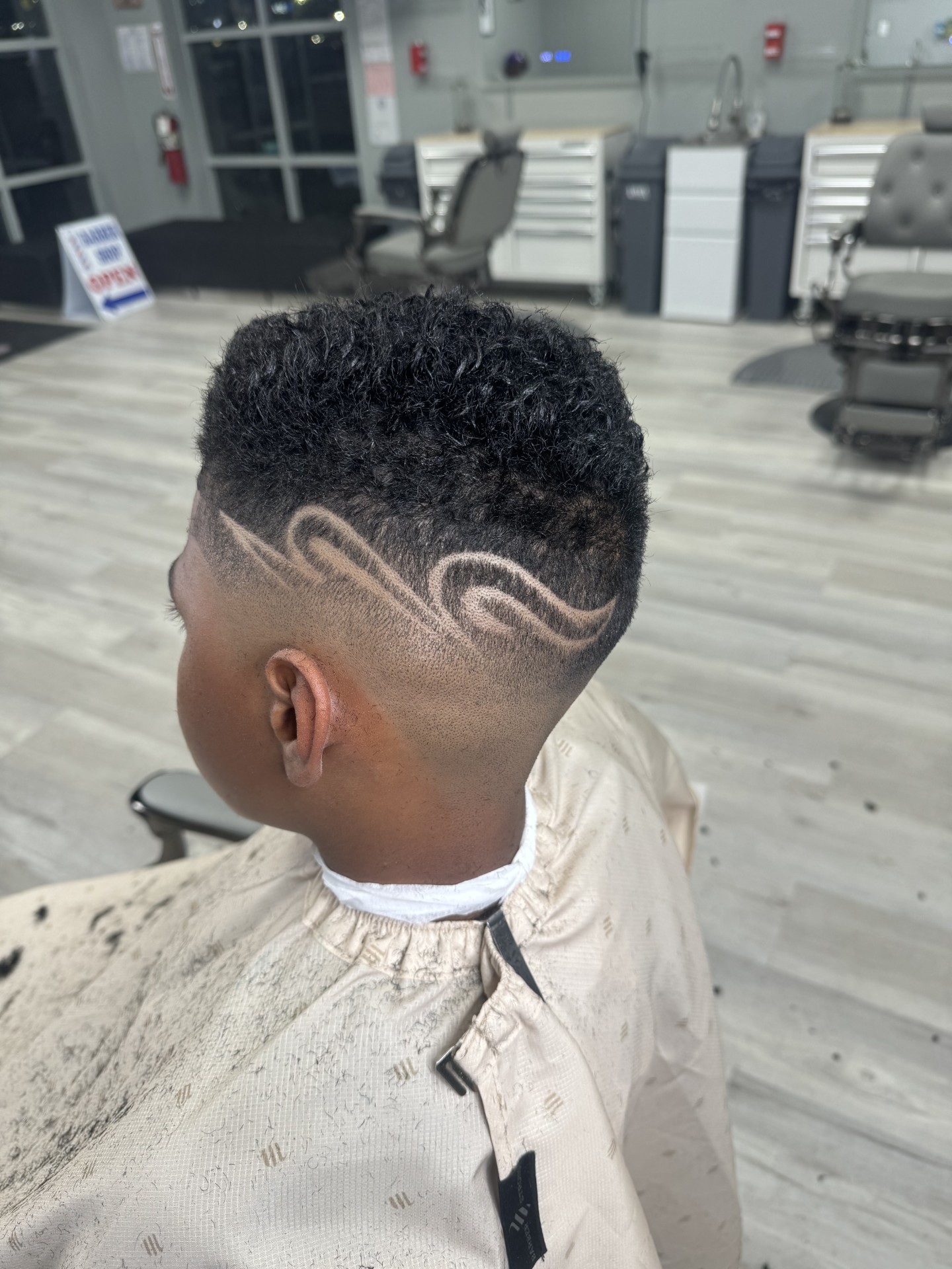 Curly top with fade and swirl hair design on the sides